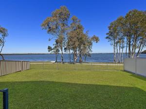 a park with a fence and a view of the water at Lake Edge Cottage in Budgewoi +5 photos