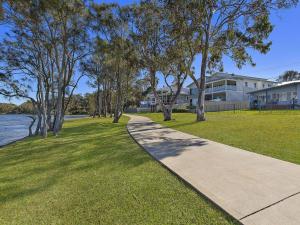 a sidewalk in a park with trees and a building at Lake Edge Cottage in Budgewoi