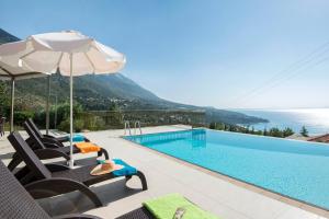 a view of a swimming pool with chairs and an umbrella at LOURDAS BEACH VIEW VILLA in Kefallonia