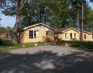 une maison en bois avec un arbre en face de celle-ci dans l'établissement Sunrise Resort, à Buckhorn