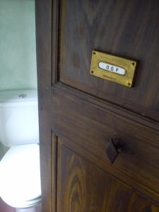 a wooden door with a clock on it next to a toilet at Domaine du Peyron in Quintenas