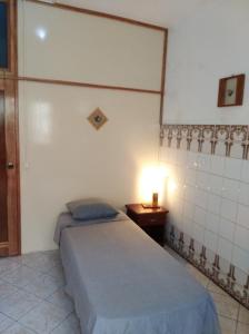 um quarto com uma cama e um candeeiro sobre uma mesa em Edificio Magico em Tarrafal