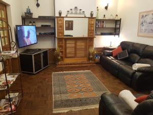 a living room with a leather couch and a flat screen tv at Barossa Glen ~ Henri's Cottage ~ Bed & Breakfast in Rosedale