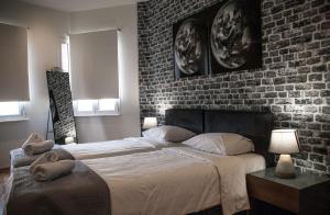 a bedroom with two beds and a brick wall at The Athens Version Luxury Suites in Athens