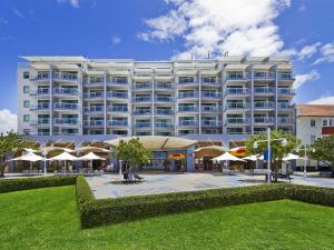 un gran edificio blanco con sombrillas delante en Waterfront Apartment 521, en The Entrance