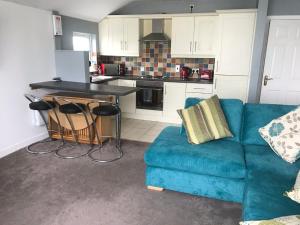 ein Wohnzimmer mit einem blauen Sofa und einer Küche in der Unterkunft Golden Sands in Portrush