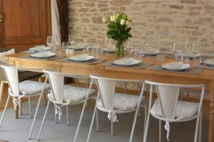 a long wooden table with white chairs and a vase of flowers at Le Clos Millot in Beaune