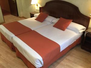 een slaapkamer met 2 bedden met oranje en witte lakens bij Hotel Cordón in Burgos