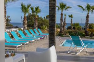 eine Reihe von Liegestühlen neben einem Pool in der Unterkunft Faros BeachFront Villa in Perivolia