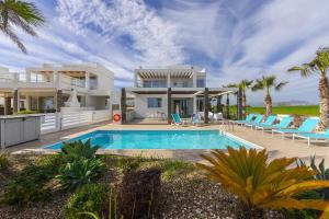 a villa with a swimming pool in front of a house at Faros BeachFront Villa in Perivolia