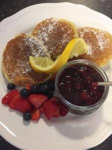 a plate with pancakes and berries and a jar of jam at Benbulben Farmhouse B&B in Drumcliff