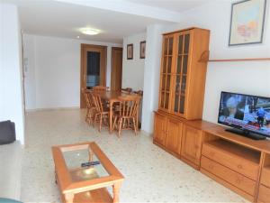 uma sala de estar com uma televisão e uma mesa de jantar em SALINAS III - PLAYA DE GANDIA ( Sólo alquiler Familias ) em Gandia