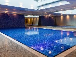 a large swimming pool with blue water in a building at Euro Apartments Szafarnia Delux in Gdańsk