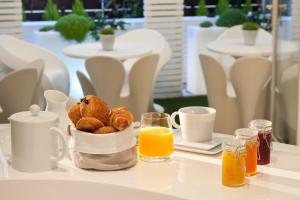 a table with a basket of pastries and orange juice at Le 7 Eiffel Hotel by Malone in Paris