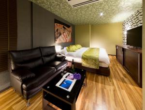 Habitación de hotel con cama y sofá de cuero en HOTEL BYAKKA, en Kagashima