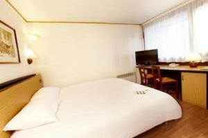 Pokój hotelowy z białym łóżkiem i biurkiem w obiekcie Campanile Moulins Avermes w mieście Avermes