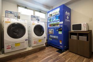 a laundry room with two washing machines and a tv at HOTEL MYSTAYS Shinsaibashi in Osaka