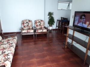 ein Wohnzimmer mit 2 Stühlen und einem Flachbild-TV in der Unterkunft Condomínio Praia de Marrakesch in Guarujá