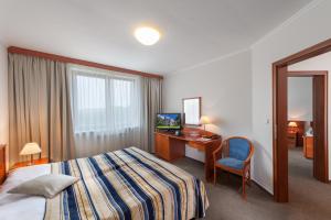 リフノフ・ナト・クニェジュノウにあるApril hotel Panoramaのベッド、デスク、テレビが備わるホテルルームです。