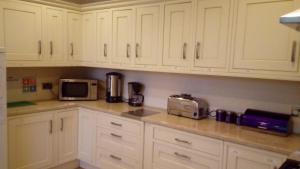 a kitchen with white cabinets and a microwave at Carer 4 You Residential Home in Upholland