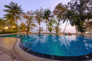 乔治市Mercure Penang Beach的有棕榈树和大海的游泳池