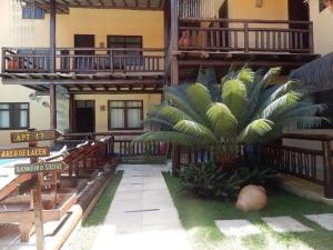 a building with a palm tree in front of it at Pousada Capitães de Areia in Porto De Galinhas