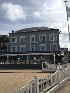 een groot gebouw met een wit hek ervoor bij Les Embruns in Trouville-sur-Mer