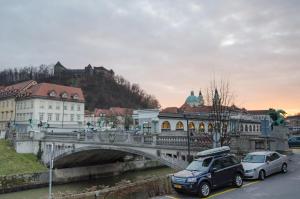 a bridge over a river with cars parked on the street at Cha Cha Rooms in Ljubljana