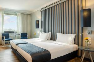 a hotel room with a large bed and a table at HF Ipanema Park in Porto
