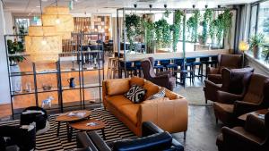 a lobby with a couch and chairs and a bar at Amrâth Apart-Hotel Schiphol Badhoevedorp in Badhoevedorp