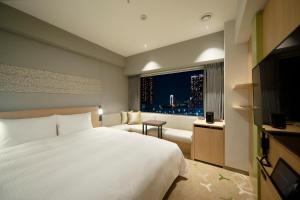 um quarto com uma grande cama branca e uma janela em Miyako City Tokyo Takanawa em Tóquio
