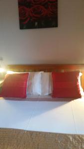Una cama con dos almohadas rojas y blancas. en Broomfield House Bed and Breakfast en Earlston