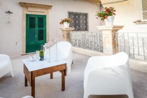a table and chairs on a balcony with a green door at Scicli Albergo Diffuso in Scicli