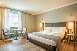 a hotel room with a bed and a table and chairs at HF Ipanema Park in Porto