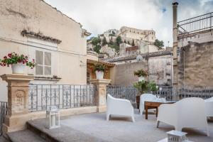 a patio with white chairs and a table and a building at Scicli Albergo Diffuso in Scicli