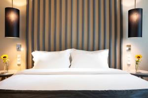 a bedroom with a large white bed and two lamps at HF Ipanema Park in Porto
