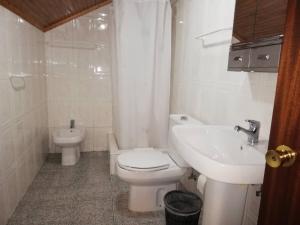 a white bathroom with a toilet and a sink at Residência Livramento in Velas