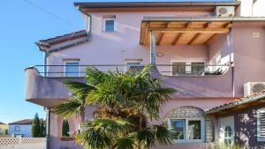 um edifício cor-de-rosa com uma palmeira à frente. em Apartment Medulin em Medulin