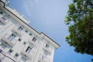 un edificio bianco con balconi e un albero di Hotel Villa Mare a Riccione