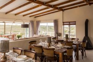 a dining room with tables and chairs and windows at Stoneyvale Cottages in Grahamstown