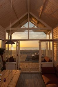 ein Wohnzimmer mit Blick auf den Strand in der Unterkunft Surf en beach strandhuisjes in Katwijk