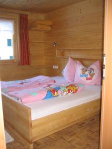 a bed in a wooden room with pink pillows at Apart Greber in Andelsbuch