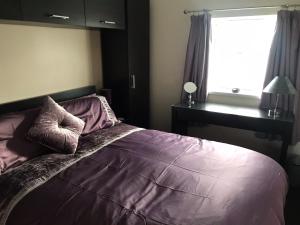 ein Schlafzimmer mit einem Bett mit violetter Bettwäsche und einem Fenster in der Unterkunft Golden Sands in Portrush