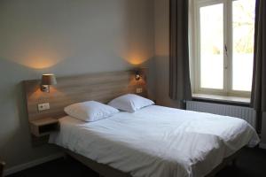 een slaapkamer met een wit bed en een raam bij Hotel Lodewijk Van Male in Brugge