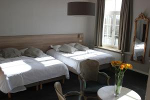um quarto com duas camas e uma mesa com um vaso de flores em Hotel Lodewijk Van Male em Bruges