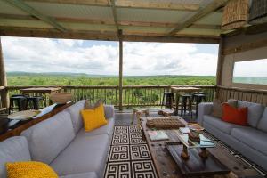 a living room with couches and a table on a deck at Zululand Lodge in Hluhluwe