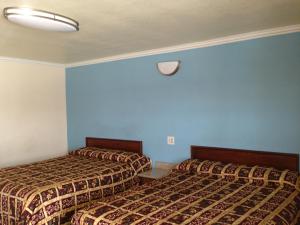 2 camas en una habitación de hotel con paredes azules en Value Inn, en Sylmar