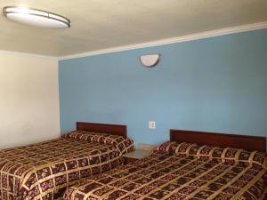 two beds in a hotel room with blue walls at Value Inn in Sylmar