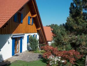 una casa con techo rojo y ventanas azules en Ferienwohnung am Kneipp-Park en Scheidegg