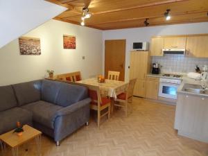 ein Wohnzimmer mit einem Sofa und einem Tisch sowie eine Küche in der Unterkunft Ferienwohnung am Kneipp-Park in Scheidegg